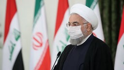Hassan Ruhani bei einer Pressekonferenz vor iranischen Flaggen