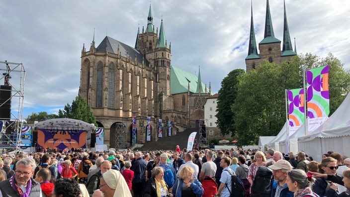Eine bunte Menschenmenge hat sich vor einer Bühne am Erfurter Dom versammelt