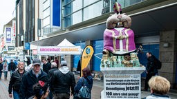 Passanten gehen am 03.10.2019 in der Kieler Innenstadt an dem so genannten Geldhamster vorbei, einer vier Meter hohen Figur der kirchenkritischen Ralf-Giordano-Stiftung. 