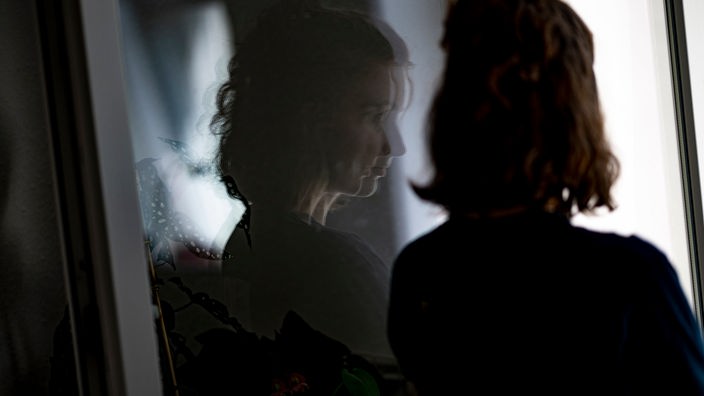 Das Beitragsbild des Dok5 "Tabu - Wenn ein Geheimnis das Leben im Griff hat" zeigt eine Frau alleine am Fenster stehend indem sie sich spiegelt. 