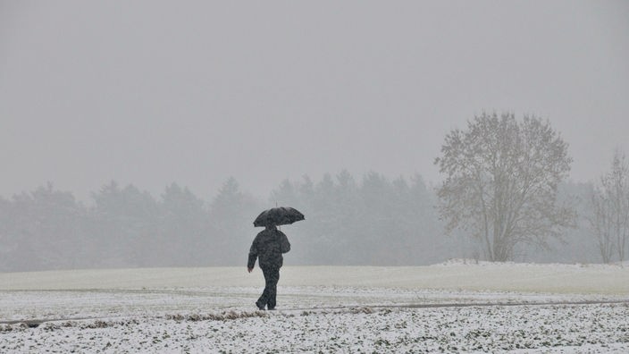 Das Beitragsbild des Dok5 Feature "Einsamkeit" zeigt einen einsamen Mann mit Regenschirm im Schneefall.
