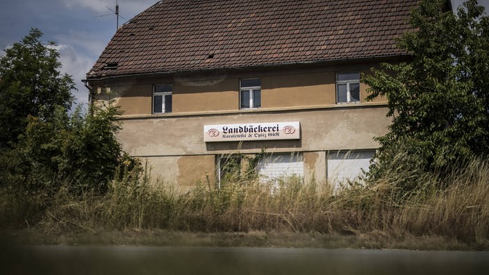 Zerfallenes, leerstehendes Haus mit Reklametafel einer Landbäckerei