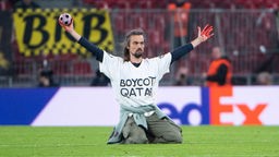 Das Beitragsbild Dok5 "Fußballkapitalismus - Ein Fan wird kritisch" zeigt einen Aktivisten auf dem Fußballfeld der ein T-Shirt trägt mit der Aufschrift Boycott Qatar.