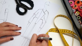Symbolbild: Weibliche Hände zeichnen eine Modeskizze.