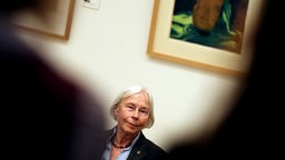 Jutta Bohnke Kollwitz sitzt in Ausstellung vor einem Bild