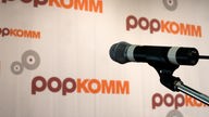 (Symbolbild) Hat die Popkomm nach Köln geholt: Manfred Post: ein Mikrophon vor einem Werbeplakat der Popkomm.