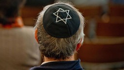 Mann mit einer Kippa sitzt in der Synagoge in Dresden. 