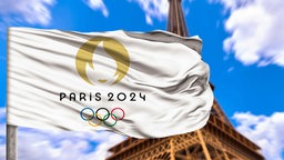 Flagge der Olympischen Spiele weht vor dem Eiffelturm in Paris, 18.07.2024.