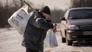 Ein Mann trägt Säcke mit Gütern, die er als humanitäre Hilfe erhalten hat.