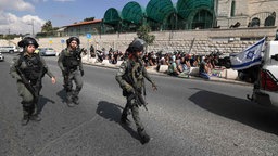 Muslimische Palästinenser nehmen am Freitagmittagsgebet teil, während die israelische Polizei im Ostjerusalemer Stadtteil Ras al-Amud vorbeigeht.