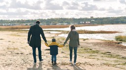 Eltern und Kind gehen zusammen am Ufer spazieren