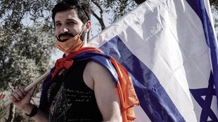 Das Bild zeigt einen armenischen Bewohner Jerusalems mit einer Fahne Armeniens und einer israelischen Fahne. Das Foto ist 2020 bei Protesten in Jerusalem im Kontext des armenisch-aserbaidschanischen Konflikts um Berg-Karabach entstanden. 