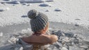 Eine junge Frau in einem Wasserloch beim Eisbaden