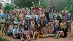 Freiwillige Helfer aus verschiedenen Ländern posieren gutgelaunt im Sadhana Forest in Auroville, Indien.