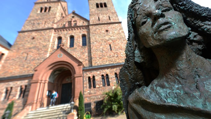 Eine Bronzestatue der Heiligen Hildegard von Bingen des Künstlers Karlheinz Oswald steht  vor der Kirche der Abtei St. Hildegard.
