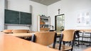 Tische und Stühle stehen in einem Klassenraum im Aloisiuskolleg in Bonn am 8. Juli 2019. Über der Tür hängt ein Kruzifix.