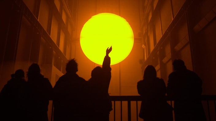 Aufnahme der Lichtinstallation 'The Weather Project' von Olafur Eliasson, die den Eindruck einer aufgehenden Sonne im Inneren der Tate Modern vermittelt.