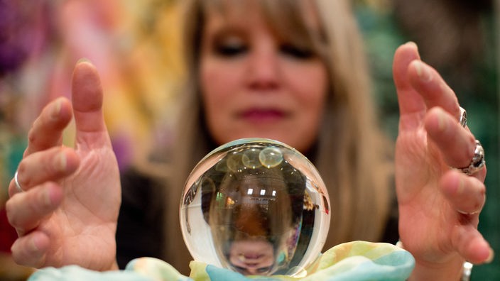 Eine Wahrsagerin blickt auf einer Esoterik-Messe in eine Kristallkugel.