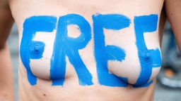 Eine Teilnehmerin einer Fahrraddemo in Berlin unter dem Motto "No Nipple is free until all Nipples are free!" hat auf ihrer Brust den Schriftzug "Free" stehen.
