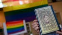Ein Imam hält bei der Vorstellung der Anlaufstelle Islam und Diversity (AID) der Ibn Rushd-Goethe Moschee ein Koran vor eine Regenbogenflagge.