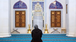 Eine Frau kniet in einer Moschee und betet