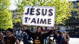 Ein evangelikaler Missionar auf dem Platz der Republik hält ein Plakat mit der Aufschrift "Jesus liebt Dich" in die Höhe 