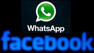 Illustration - Das Logo des Kurznachrichten-Dienstes WhatsApp ist auf einem Smartphone zu sehen, welches vor das Logo des weltgrößten sozialen Online-Netzwerkes Facebook gehalten wird