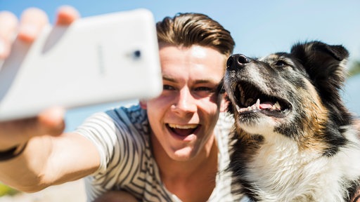 Hund und Mann machen Selfie.