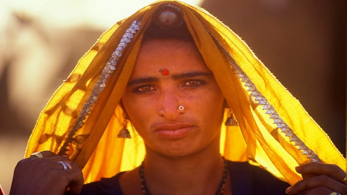 Das Gesicht einer indischen Frau mit einer gelben Kopfbedeckung