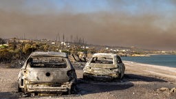 Zwei ausgebrannte Autos am Strand