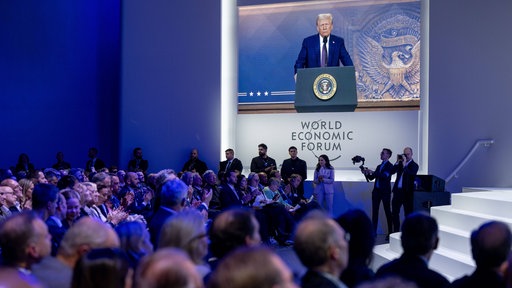 Beim Weltwirtschaftsforum in Davos 2025 ist auf einer Leinwand vor Publikum Donald Trump zu sehen, der per Videokonferenz zugeschaltet ist