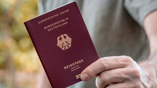 Hand hält deutschen Reisepass in die Kamera