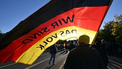 "Wir sind das Volk" steht auf einer Deutschland-Fahne, die ein Teilnehmer auf einer Kundgebung der Thüringer AfD trägt.