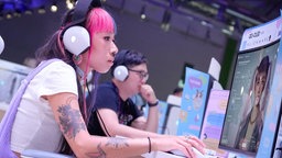 Eine Besucherin der Gamescom 2024 in Köln an einem Computer