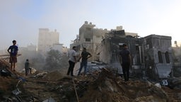 Menschen stehen nach einem israelischen Raketenangriff auf den Trümmern in Gaza-Stadt