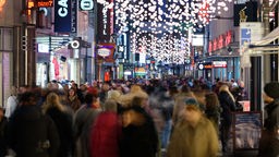 Passanten gehen durch die Shoppingmeile in der Hohe Straße in Köln im Advent. 
