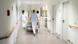 Krankenschwestern schieben ein Bett durch ein Krankenhaus.