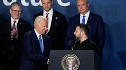 Joe Biden schüttelt Volodomir Selensky hinter dem Rednerpult des NATO-Gipfels die Hand