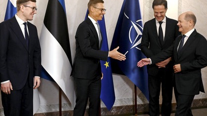 Der finnische Präsident Alexander Stubb begrüßt Bundeskanzler Olaf Scholz zu Beginn des NATO-Treffens. Daneben stehen der estnische Premierminister Kristen Michal (links) und Nato-Generalsekretär Mark Rutte.