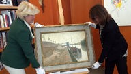 Kulturstaatsministerin Monika Grütters und die Erbin der rechtmäßigen jüdischen Besitzer halten ein Gemälde von Paul Signac
