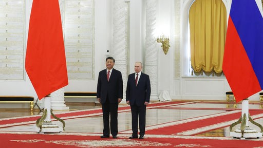 Xi Jonping und Putin stehen im Kreml zwischen einer chinesischen und einer russischen Flagge