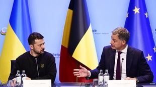 Selenskyj und De Croo vor Flaggen der Ukraine, Belgien und der EU