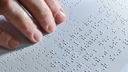 Ein Mensch liest einen Text in Braille-Schrift