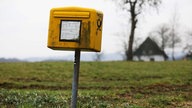 Ein schmutziger Briefkasten auf einer Wiese.