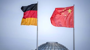 Symbolbild: Die chinesische und deutsche Fahne vor der Kuppel des Reichstags.