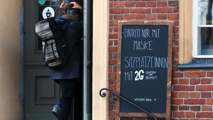 Symbolbild: Hinweis auf Maskenpflicht und 2G-Regel am Eingang eines Restaurants