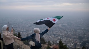 Eine junge Frau posiert für ein Foto mit einer syrischen "Revolutions"-Flagge an einem Aussichtspunkt auf dem Berg Qasiyun oberhalb der Stadt Damaskus. 