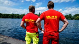 Zwei Menschen mit DLRG-Shirt stehen an einem See (2021).