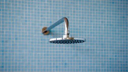 Ein Duschkopf an einre blau gekachelten Wand