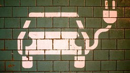 Ein Symbol markiert einen Parkplatz mit einer öffentlichen Ladesäule für Elektroautos.